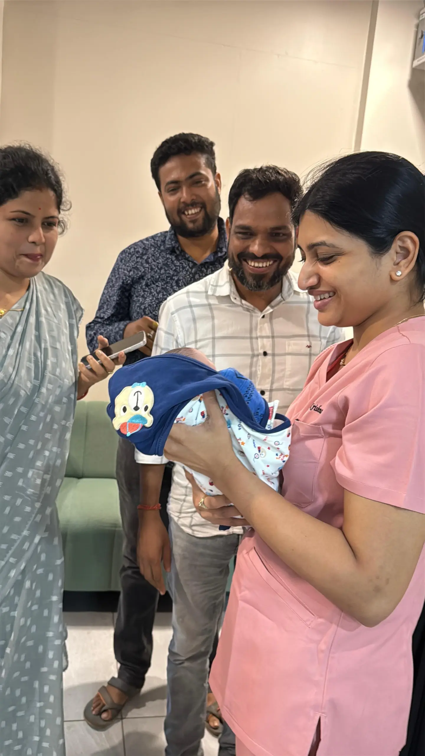 Newborn in a neonatal incubator being cared for by a nurse in blue scrubs in a NICU, with monitors and equipment nearby into the scene.